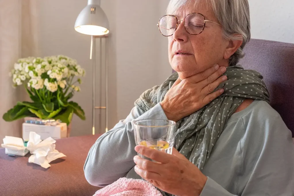 Elderly adult caucasian woman with sore throat and fever as seas